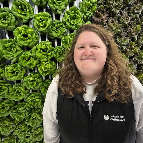 Taylor stands next to lettuce growing in the freight farm