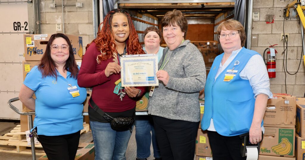 MOFC's Laurie Coleman presents a certificate of recognition to Chutnee Harper (center, in red), Food and Consumables Coach at the Lewis Center Walmart. The store donated more than 80,000 pounds of food to MOFC's hunger relief network in 2023.