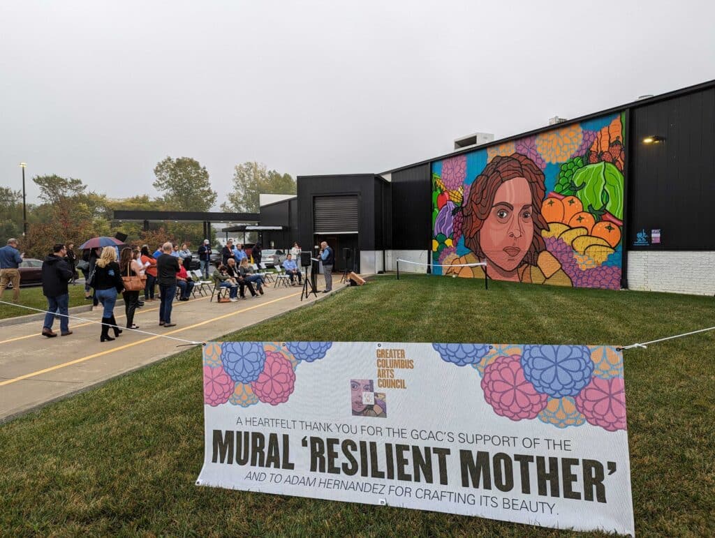 The Resilient Mother mural is unveiled. People gather near.