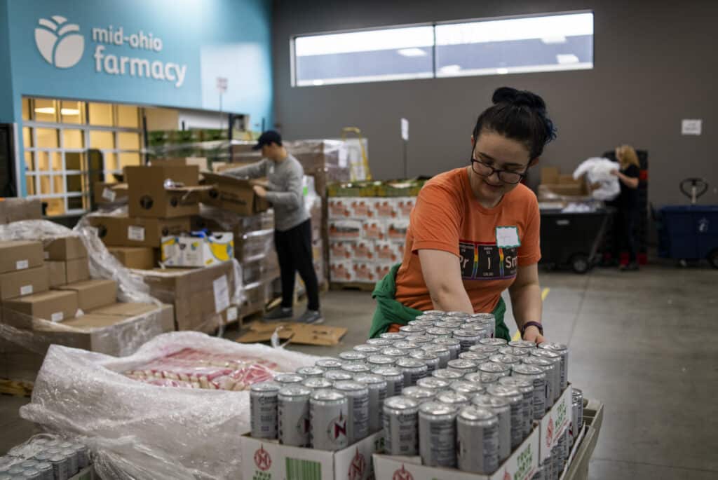 Volunteer sorts through pallets of cans