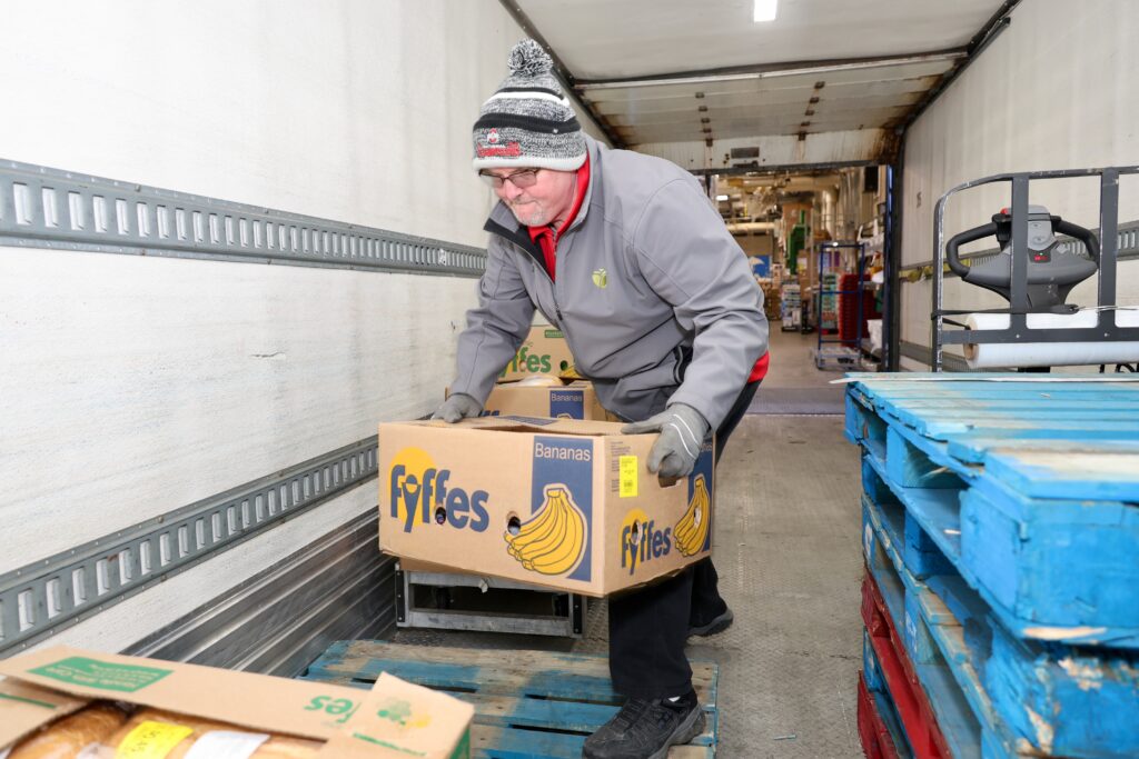 Mid-Ohio Food Collective truck driver picks up a box of bananas on the truck