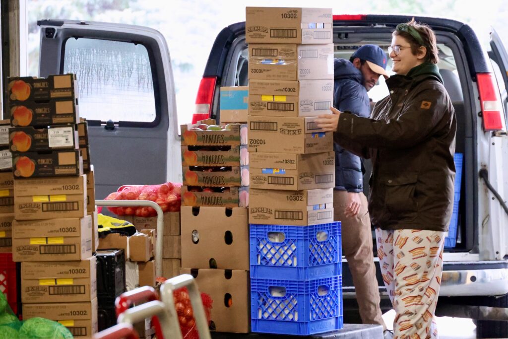 Volunteers take boxes of food off a truck 
