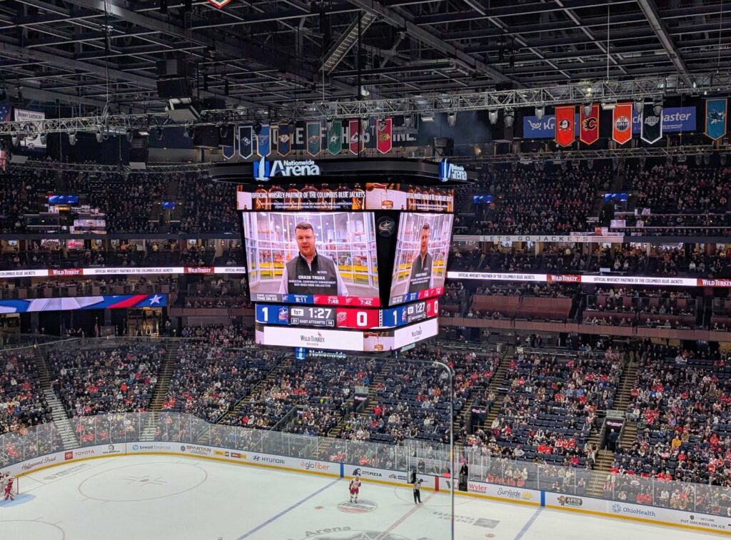 A screen at the Columbus Blue Jackets home stadium shows a video of MOFC Director of Corporate Engagement talking about MOFC. 