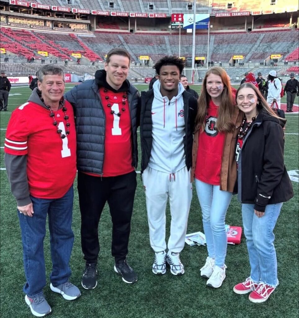 Raffle winner Brianna Allman and family pose next to OSU football safety Caleb Downs. 