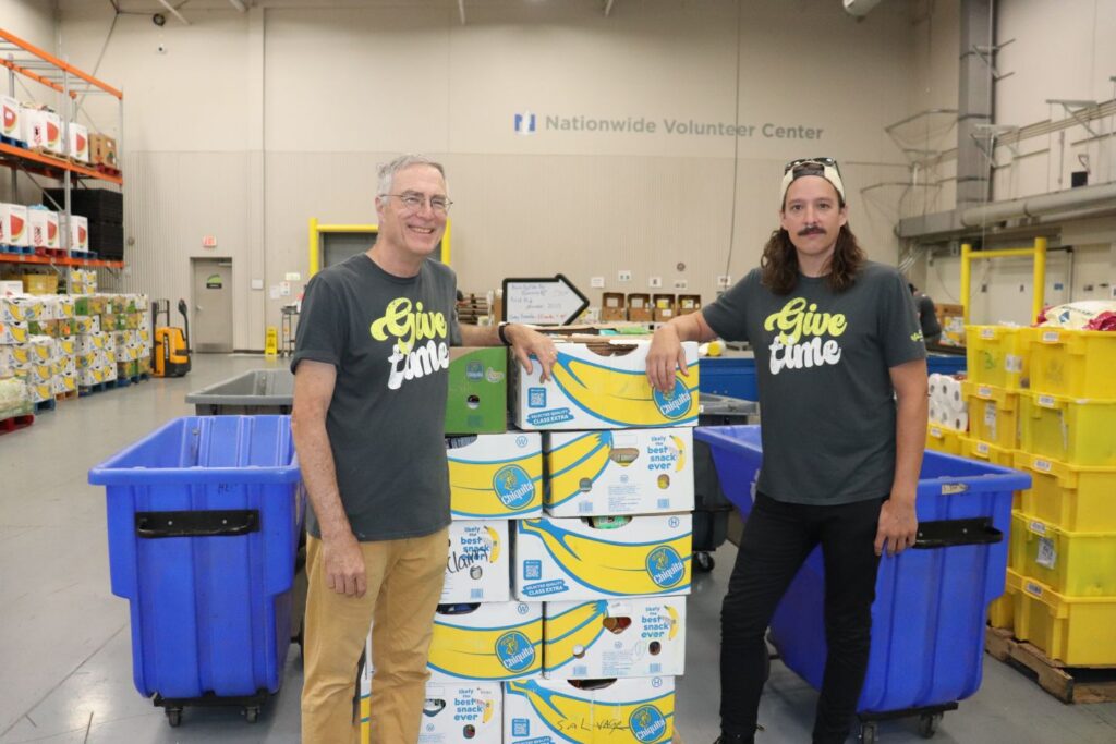 Father and son Ed and Ben pose in front of boxes to be sorted through at the Mid-Ohio Foodbank.