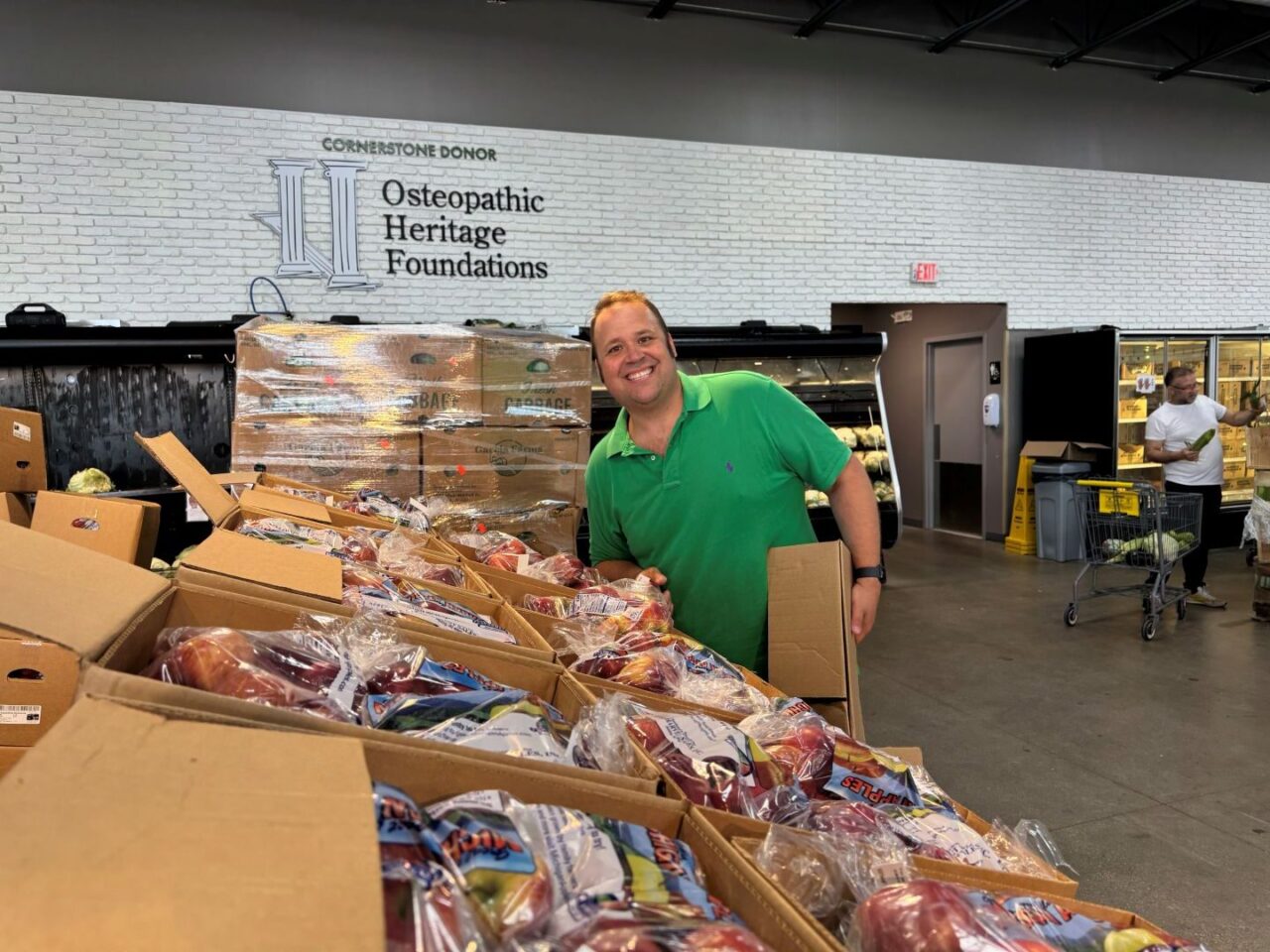 Volunteer at the Mid-Ohio Market at Norton Road smiles at camera while unloading boxes of produce.